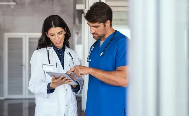 Nurse teacher reviewing patient charts with nursing student in blue scrubs